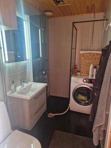 a bathroom with a sink and a washing machine at Compact beautiful apartment with sauna in Kuusamo