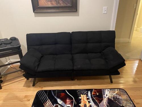 a black couch in a living room with a table at Temple View Inn with Music Studio in Independence
