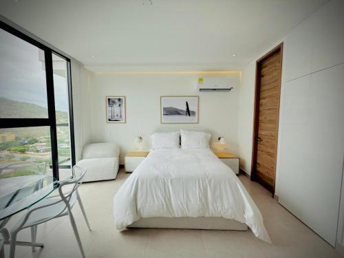 a white bedroom with a bed and a chair at Modern Beach Retreat Luxury Feel in Playa Bello Horizonte