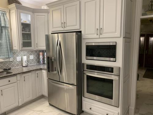 a kitchen with white cabinets and stainless steel appliances at Temple View Inn with Music Studio in Independence