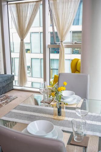 a dining room with a table with plates and glasses at Mory Homes Modern 2 BDR Flat Private Parking in Central MK in Milton Keynes