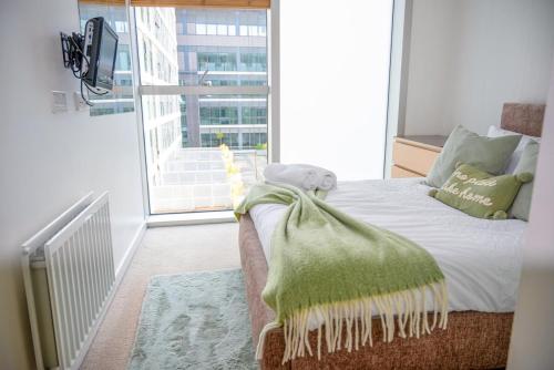 a bedroom with a bed with a green blanket on it at Mory Homes Modern 2 BDR Flat Private Parking in Central MK in Milton Keynes
