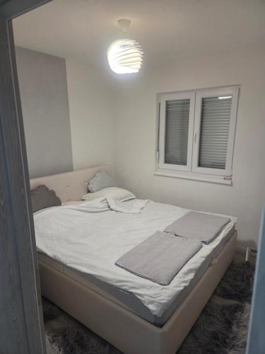 Una cama en una habitación blanca con ventana. en Kuća snova, en Ilijaš