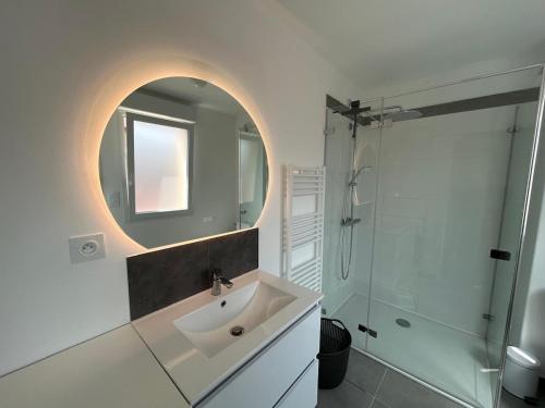 a bathroom with a sink and a mirror and a shower at Maison neuve proche plage et commerces in Stella-Plage