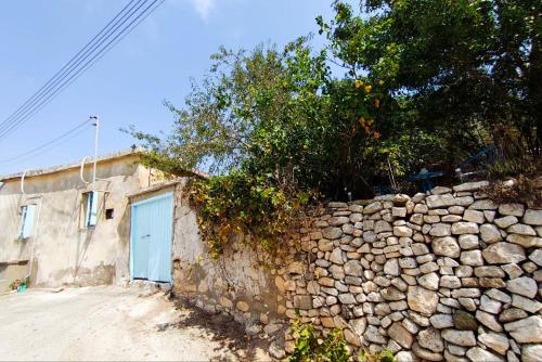 a stone wall next to a building with a blue door at DC Family Home & Garden - Traditional village house in Pano Arodes