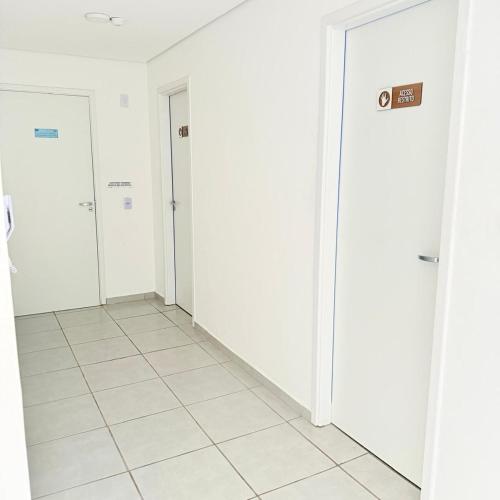 a hallway with white walls and white tile floors at 104NV Studio Liberdade SP 300 m Metro Japao, acomoda até 03 pessoas in Sao Paulo