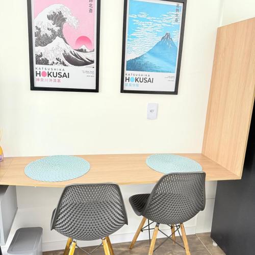 a table with two chairs and two posters on the wall at 104NV Studio Liberdade SP 300 m Metro Japao, acomoda até 03 pessoas in Sao Paulo