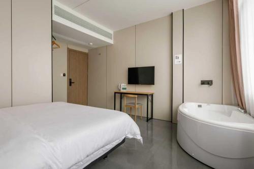 a bedroom with a bed and a tub and a television at Cloud Alley Airport Shuttle Hotel in Shanghai