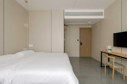 a bedroom with a bed and a desk and a television at Cloud Alley Airport Shuttle Hotel in Shanghai