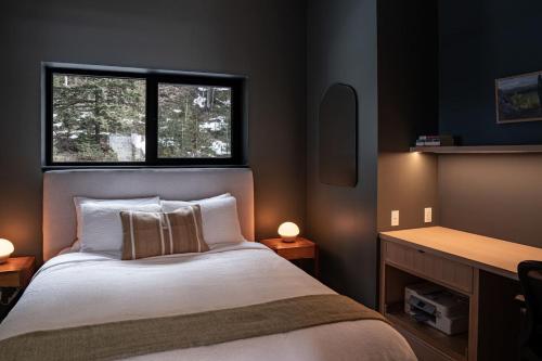 a bedroom with a bed with a desk and a window at Ghost Peak Chalet - Ski-In Access in Port Mann
