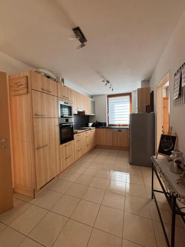 a large kitchen with wooden cabinets and a refrigerator at Apart Pitzenklamm in Arzl im Pitztal