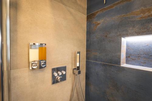 a bathroom with a wall with a shower and a mirror at Quinta Stella in Tirano