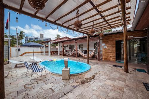 a patio with a swimming pool and an umbrella at Casa c 5 suites, Piscina, Churrasqueira e Sinuca in Cabedelo