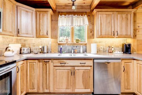 a kitchen with wooden cabinets and a sink and a window at 7 Mi to Glens Falls Peaceful Retreat with Game Room 