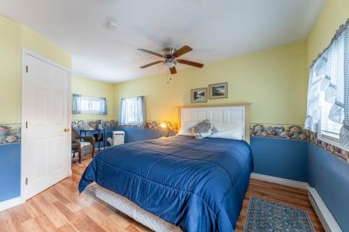 a bedroom with a blue bed and a ceiling fan at Dominion Hill Country Inn in Bocabec