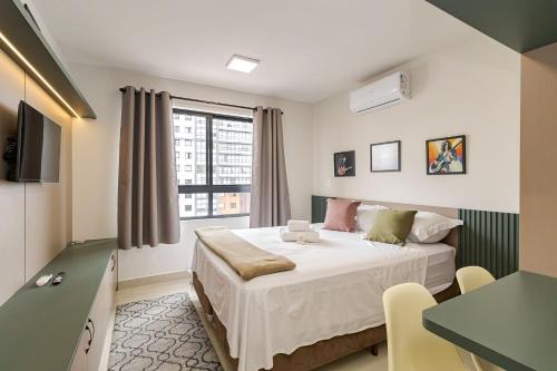 a bedroom with a bed and a desk and a window at MUV Residence - Centro | Gonzaga Stays in Curitiba
