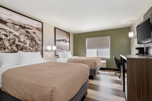 a hotel room with two beds and a flat screen tv at Quality Inn Red Lodge Gateway To Yellowstone in Red Lodge