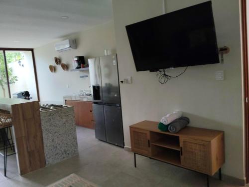 a kitchen with a refrigerator and a tv on the wall at Villa La Toscana Yucateca Encanto Italiano en Mérida in Mérida