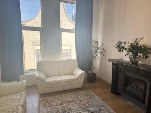 a living room with a white chair and a fireplace at Apartment in city centre in Schiedam