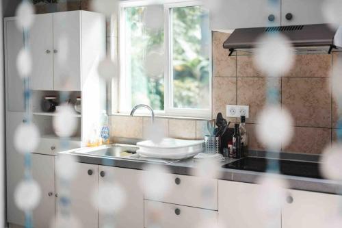 a kitchen with white cabinets and a sink and a window at Matira Blue House in Bora Bora