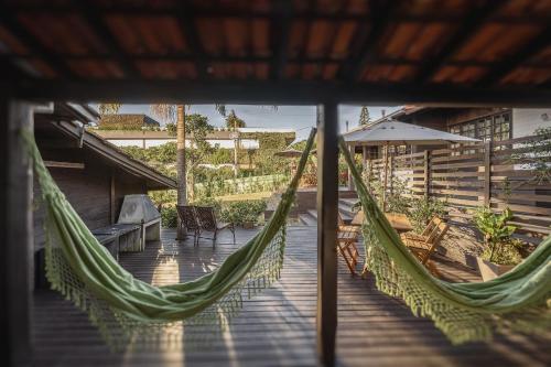 a porch with a hammock and a table and chairs at Casas Valley Design - Praia do Rosa/SC in Praia do Rosa