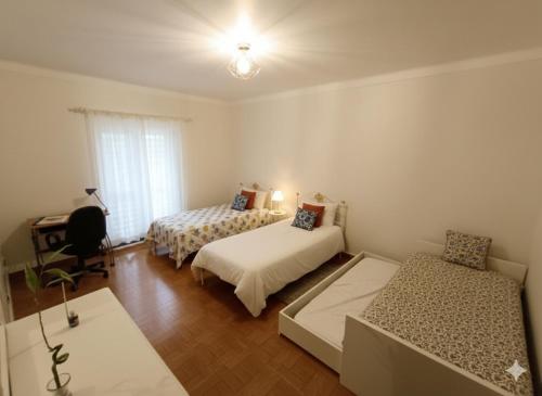 a bedroom with two beds and a desk and a window at Moradia de Campo Isolada com Piscina a 5km da Praia in Alcantarilha