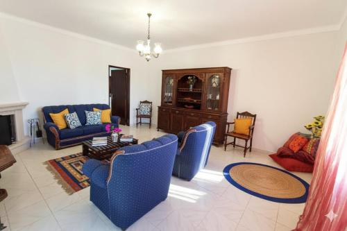 a living room with blue chairs and a couch at Moradia de Campo Isolada com Piscina a 5km da Praia in Alcantarilha