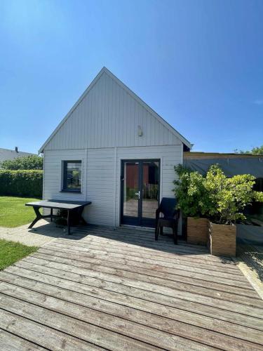 a house with a picnic table and a bench on a deck at Le petit Chalet in Port-Bail-sur-Mer