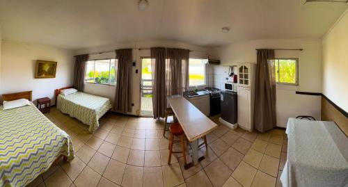 a bedroom with two beds and a kitchen with a table at Cabañas Las Terrazas in Pichilemu