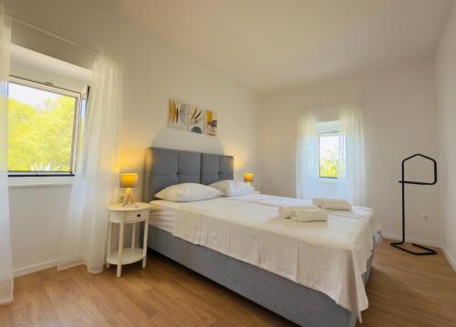 a white bedroom with a large bed and a window at Holiday Home Vista Natura in Labin