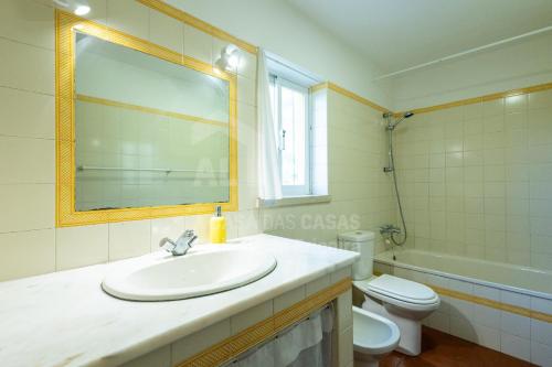 un bagno con lavandino, WC e specchio di Casa Lantana by ACasaDasCasas a Casas Velhas