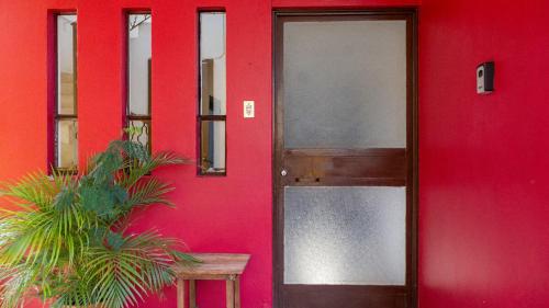 a red building with a door and a plant at Casa Centrica Con Estacionamiento in Cedro