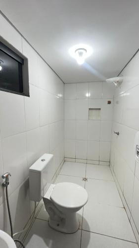 a white bathroom with a toilet and a tv at Hotel Veneza in Brasília