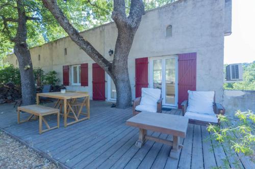 una terraza de madera con mesa, sillas y árboles en Le Mozart - Aix, en Aix-en-Provence