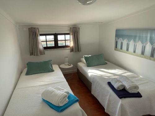 ein Schlafzimmer mit zwei Betten mit Handtüchern darauf in der Unterkunft First-Line Oceanfront House in Moledo in Moledo