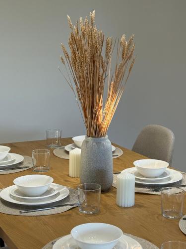 a wooden table with plates and bowls and a vase with dry grass at Theros Residence in Stavros