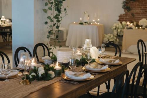 a wooden table with candles and plates and wine glasses at The Beau Hotel Downtown San Diego Gaslamp Quarter in San Diego