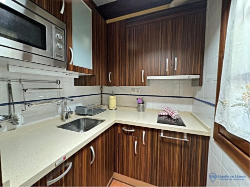 a kitchen with wooden cabinets and a sink and a microwave at Vut la huertona in Pechón