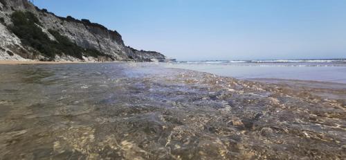 a beach with a bunch of rocks in the water at Scala dei Turchi Apartment in Realmonte
