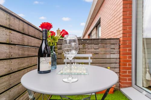 a white table with a bottle and a wine glass at Central 2Bed,2Bath, Balcony Apartment Near New Street, Mailbox & Canals at Skyline Apartments in Birmingham