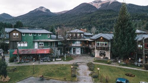 a large house with mountains in the background at Departamentos de El Mercado in Villa La Angostura