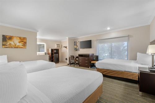 a hotel room with two beds and a desk at Best Western Courtesy Inn Hotel - Anaheim Resort at the Park in Anaheim