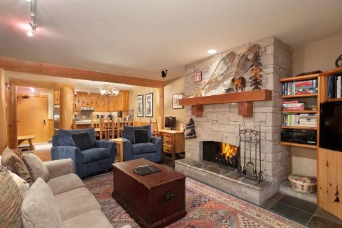 Una sala de estar con chimenea y sofás azules. en Hearthstone Lodge 3 | Central Whistler Village Condo with Sauna & Hot Tub, en Whistler