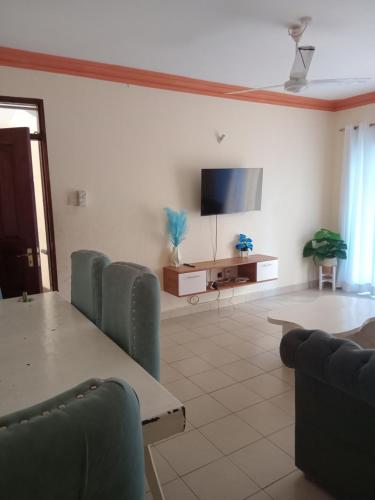 a living room with a table and chairs and a flat screen tv at Mtwapa Luxurious 3 Bedroom with Pool in Mombasa