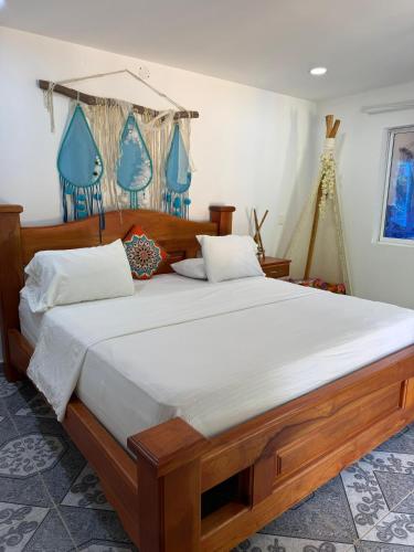 a bedroom with a large wooden bed with white sheets at Eco hotel el bosque in Doradal