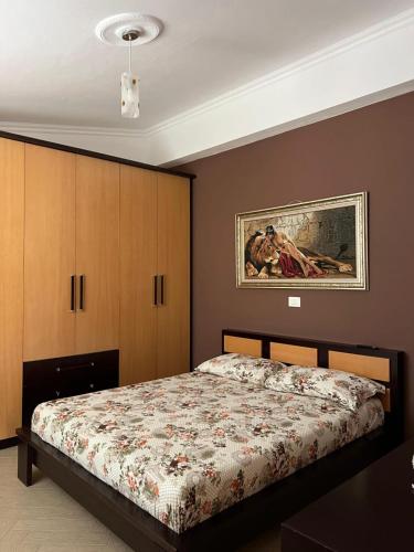 ein Schlafzimmer mit einem Bett und einem Gemälde an der Wand in der Unterkunft Ela's apartment in Orikum
