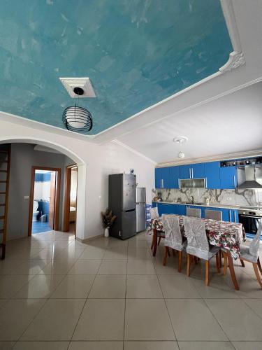 eine Küche mit blauer Decke, mit Tisch und Stühlen in der Unterkunft Ela's apartment in Orikum