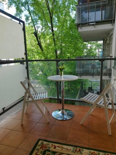 a balcony with a table and two chairs and a window at Solidarnosci155GuestRooms in Warsaw