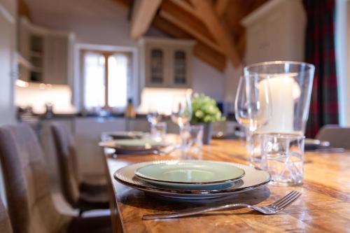 a wooden table with plates and glasses on it at Balthazar The Loft by Villars Luxury in Villars-sur-Ollon
