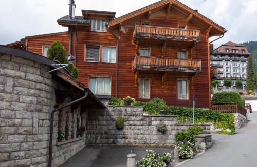 a large wooden house with a stone wall in front of it at Balthazar The Loft by Villars Luxury in Villars-sur-Ollon
